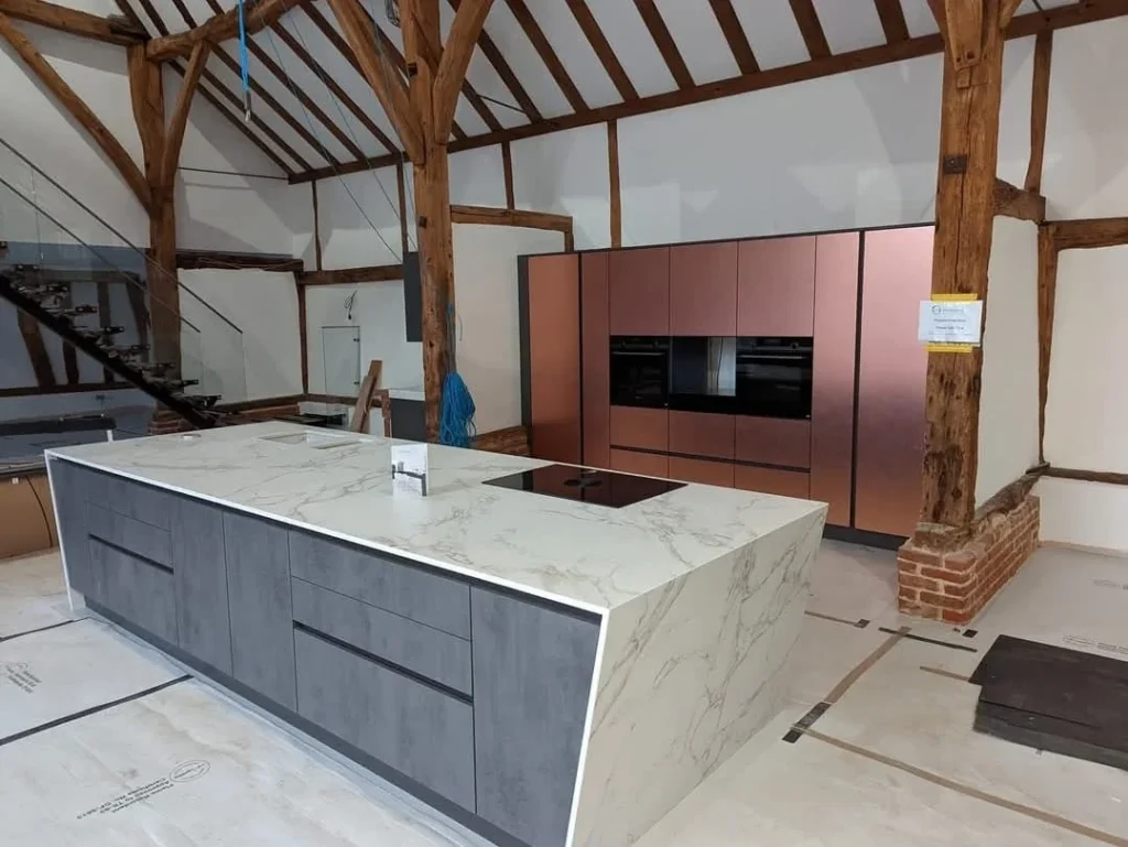 https://fixandflipconstruction.co.uk/wp-content/uploads/2026/08/barn-conversion-kitchen-exposed-beams-copper-cabinetry-1024x769.webp